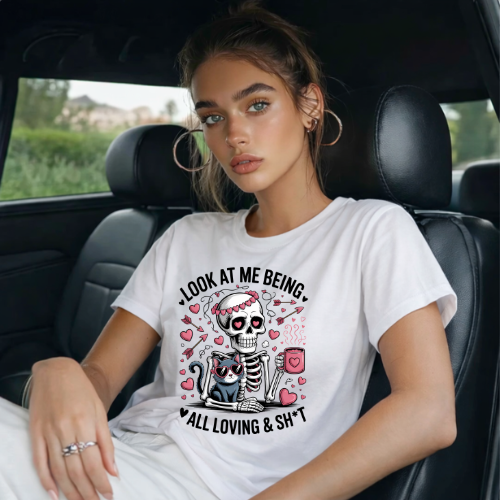 Woman sitting in a car wearing a white t-shirt with a skeleton graphic and text.