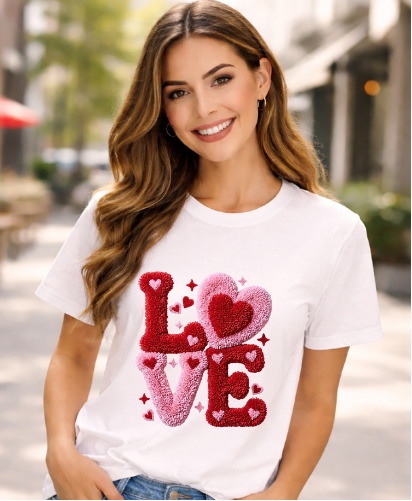 Woman wearing a white t-shirt with red and pink 'LOVE' design outdoors.