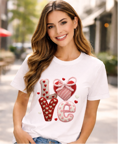 Woman wearing a white t-shirt with decorative text and graphics outdoors.