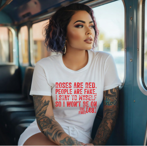 Woman sitting on a bus wearing a white t-shirt with red text.
